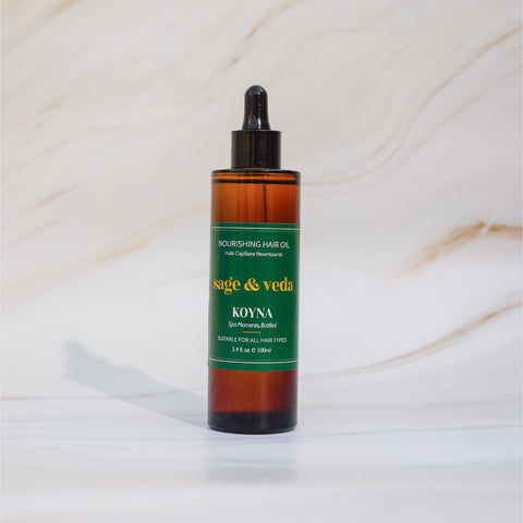 Sage & Veda Koyna Hair Oil 100ml bottle on marble background.