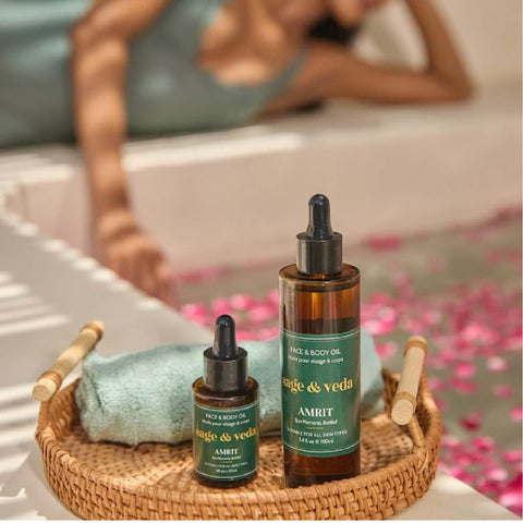 Lifestyle shot of Amrit oils (30ml & 100ml) in a woven tray, spa-like self-care ritual setting.